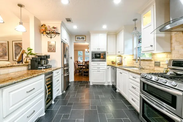 a kitchen with stainless steel appliances granite countertop a stove a sink and a refrigerator