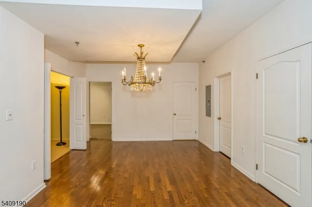 a view of empty room with wooden floor and chandelier