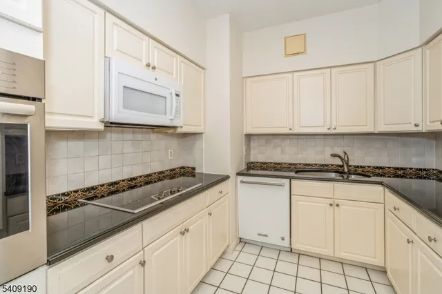 a view of a big room with wooden floor chandelier and a kitchen