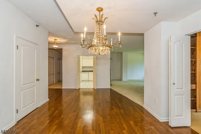 a view of empty room with wooden floor and chandelier