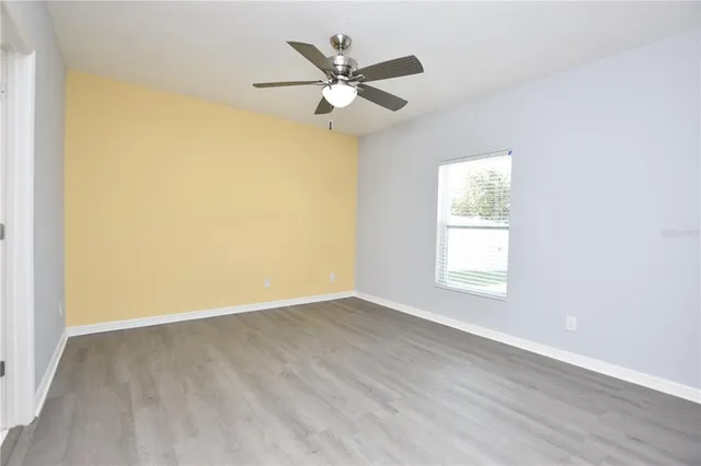 an empty room with wooden floor and ceiling fan