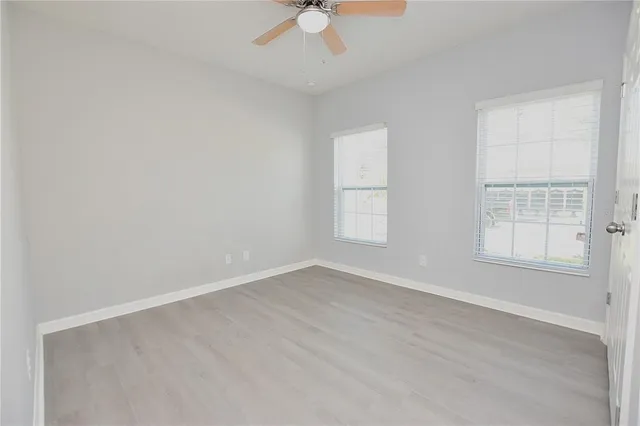 an empty room with windows and fan