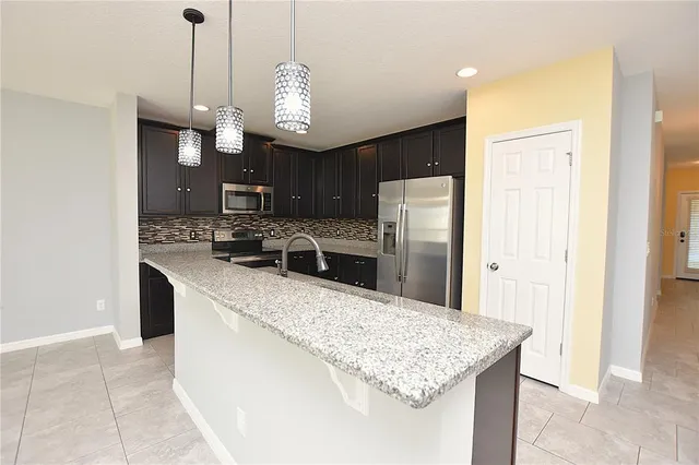 a kitchen with stainless steel appliances granite countertop a sink a refrigerator and a stove