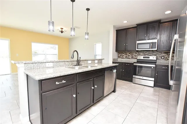 a kitchen with stainless steel appliances granite countertop a sink a stove and a refrigerator