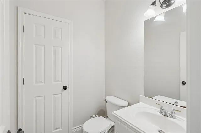 a bathroom with a toilet sink vanity and mirror