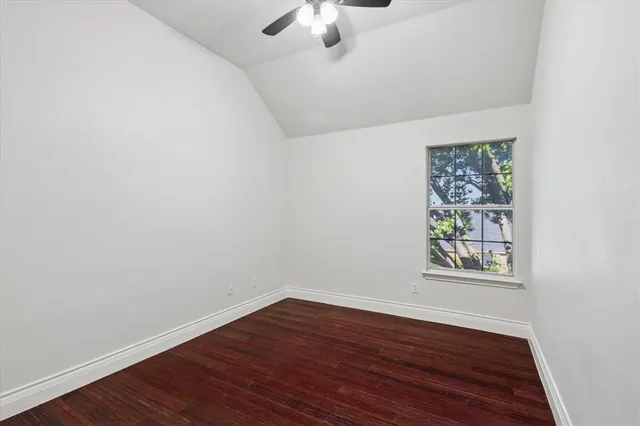 an empty room with wooden floor chandelier fan and windows