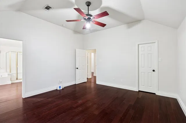 an empty room with wooden floor and ceiling fan