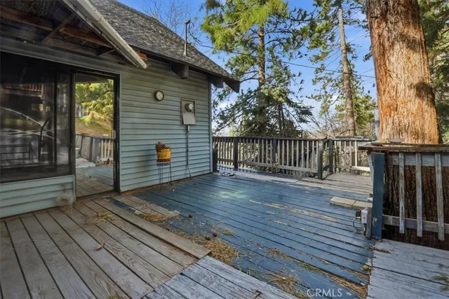 a view of a wooden house with a large tree and wooden fence