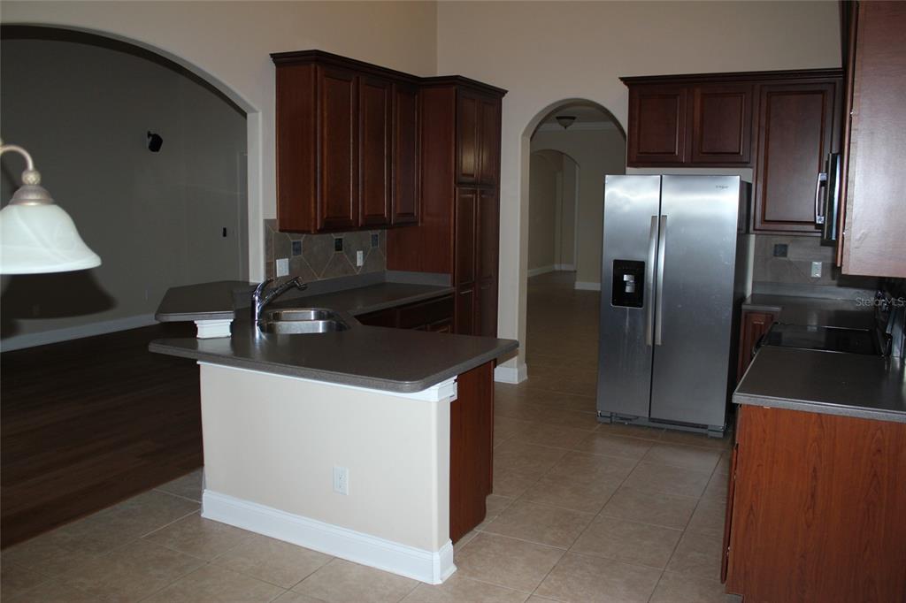 6833 Dolce Way Orlando, FL 32819 - Photo 12 of 28 a kitchen with stainless steel appliances granite countertop a refrigerator a sink and wooden cabinets