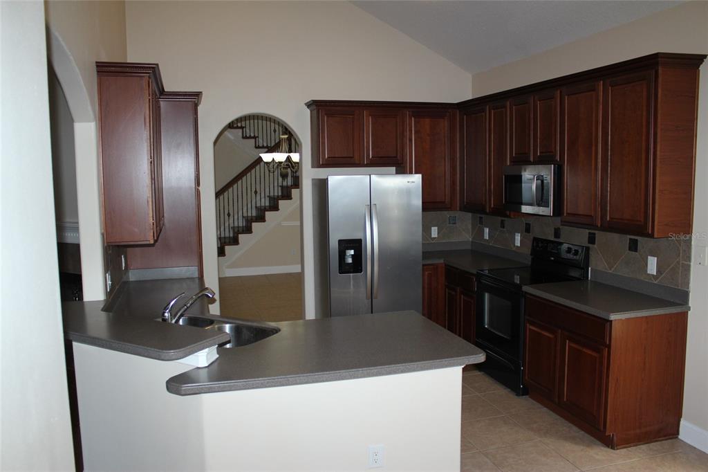 6833 Dolce Way Orlando, FL 32819 - Photo 13 of 28 a kitchen with granite countertop stainless steel appliances a refrigerator and wooden cabinets