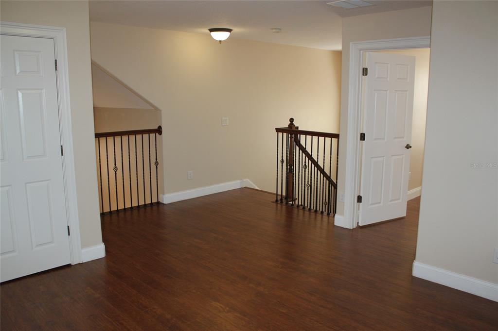 6833 Dolce Way Orlando, FL 32819 - Photo 20 of 28 a view of an empty room with wooden floor and a window
