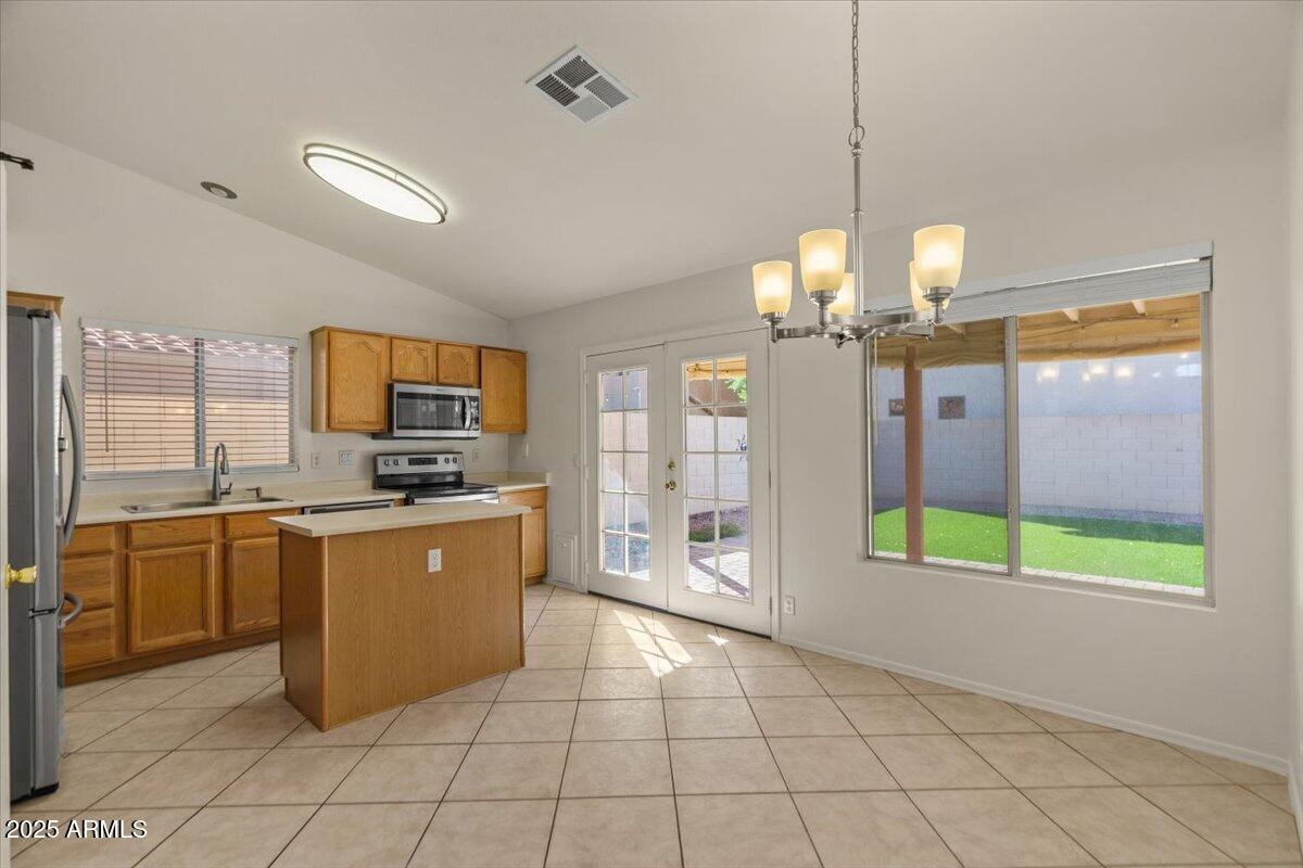 9163 West St John Road Peoria, AZ 85382 - Photo 12 of 38 a large kitchen with stainless steel appliances granite countertop a stove top oven a sink dishwasher a dining table and chairs with wooden floor