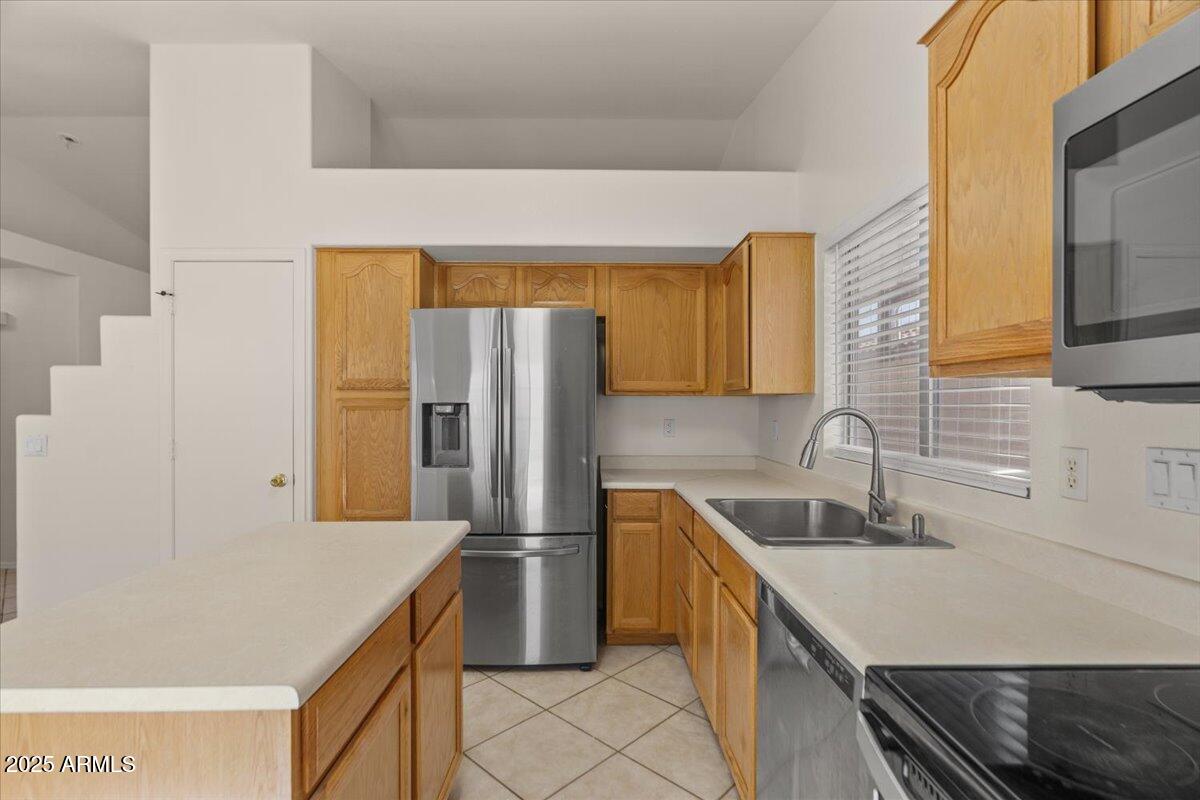 9163 West St John Road Peoria, AZ 85382 - Photo 16 of 38 a kitchen with a sink a refrigerator and a cabinets