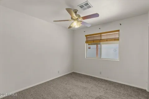 an empty room with a window and ceiling fan