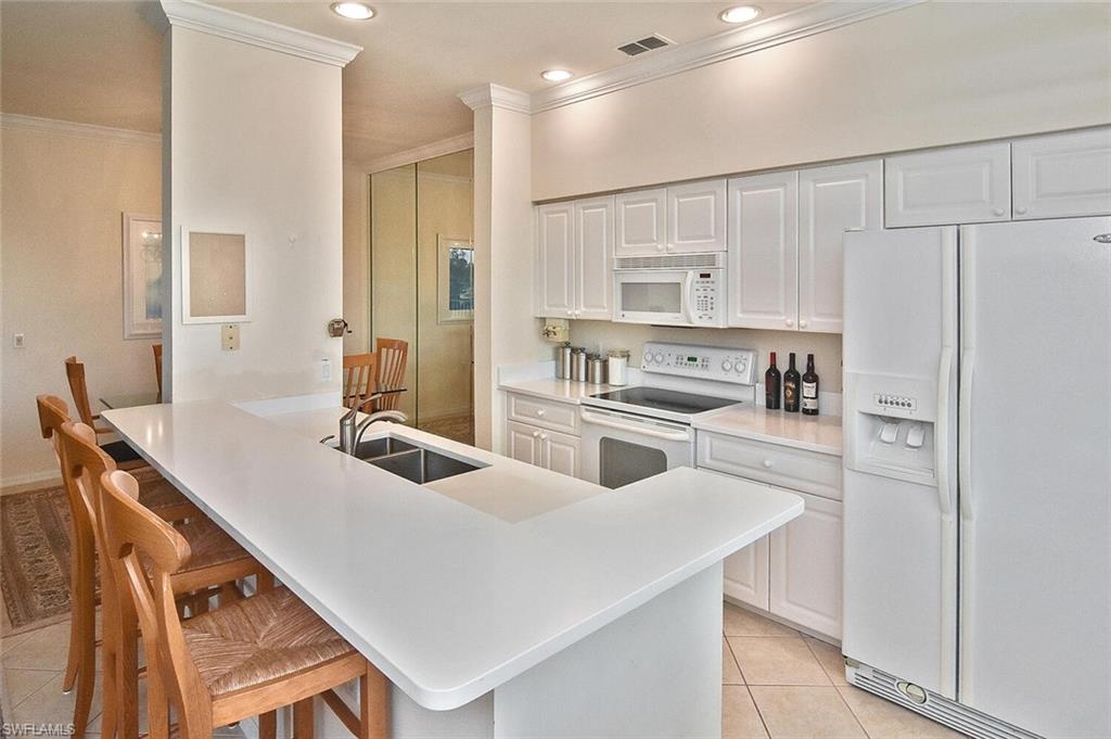 3830 Sawgrass Way, Unit 2946 Naples, FL 34112 - Photo 24 of 49 a kitchen with white cabinets and white appliances