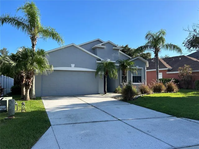 a front view of a house with a yard and palm trees