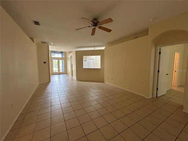 a view of an empty room with window and chandelier fan