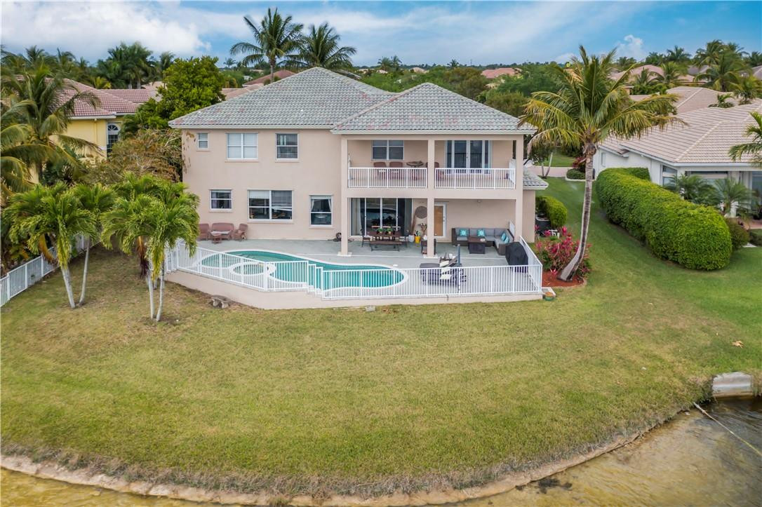4185 Southwest 186th Way Miramar, FL 33029 - Photo 17 of 92 a white house with a large pool and lawn chairs under an umbrella