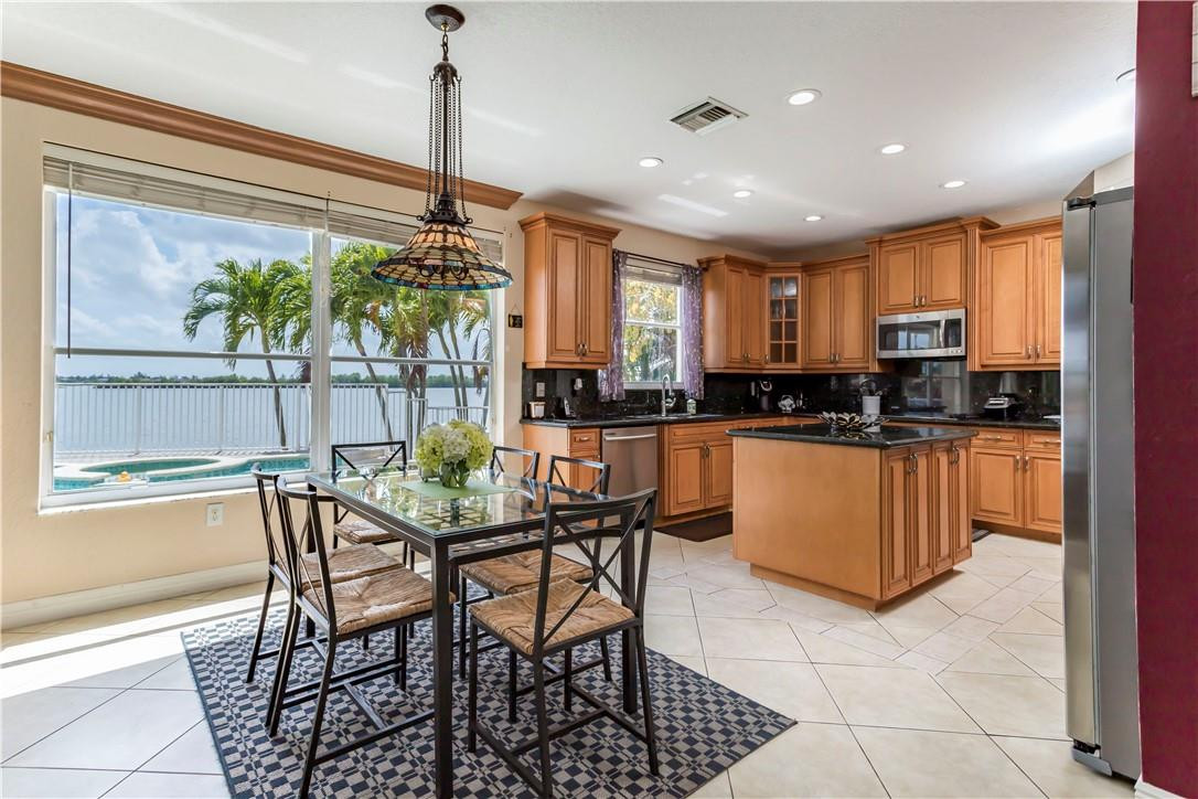 4185 Southwest 186th Way Miramar, FL 33029 - Photo 27 of 92 a kitchen with stainless steel appliances granite countertop a stove a sink a microwave a dining table and chairs with wooden floor