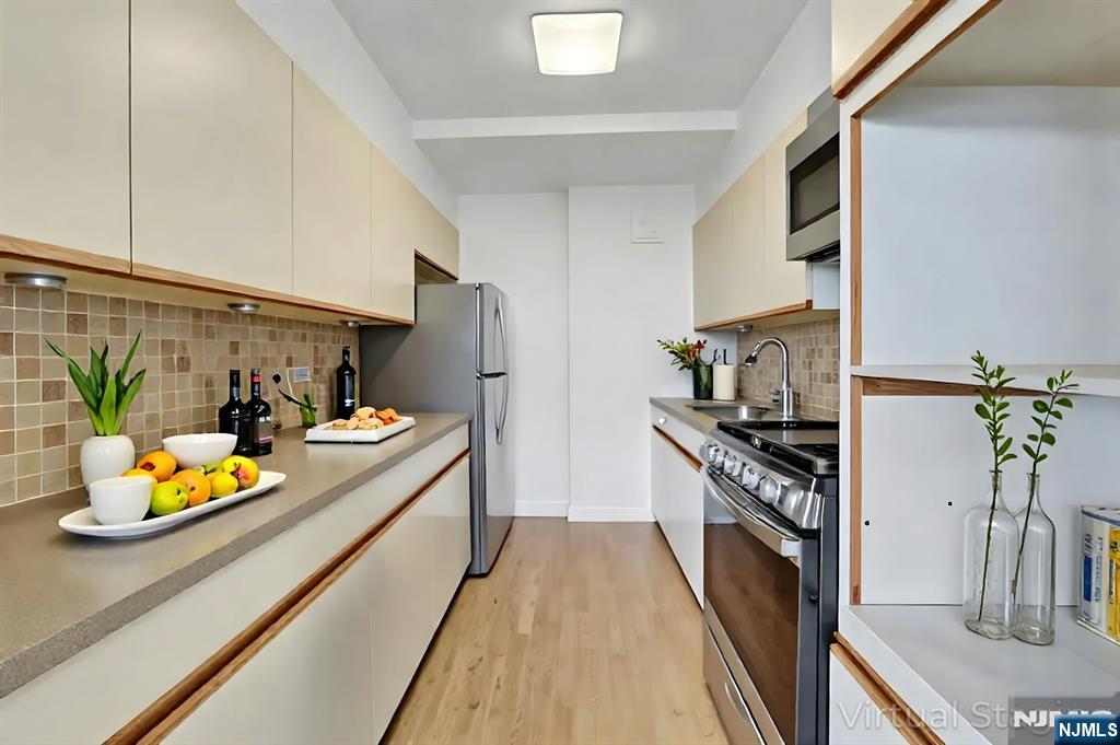 1 Horizon Road, Unit 609 Fort Lee, NJ 07024 - Photo 18 of 40 a kitchen with stainless steel appliances granite countertop a refrigerator a stove and a sink with wooden floor