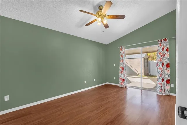 an empty room with wooden floor and a ceiling fan