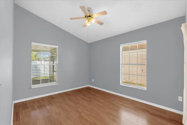 an empty room with wooden floor closet and windows