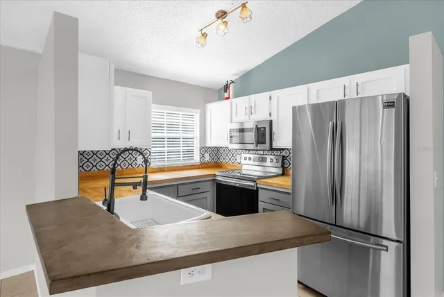 a kitchen with stainless steel appliances granite countertop a refrigerator a sink dishwasher a stove and white countertops with wooden floor