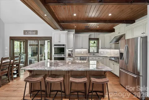 a kitchen with stainless steel appliances granite countertop a table chairs and a refrigerator