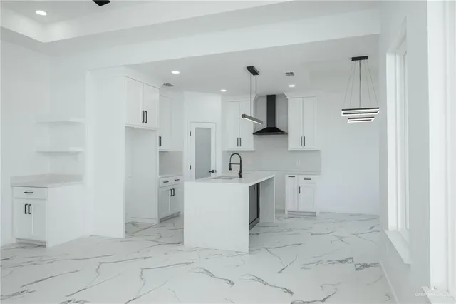 a large white kitchen with a sink stainless steel appliances and cabinets