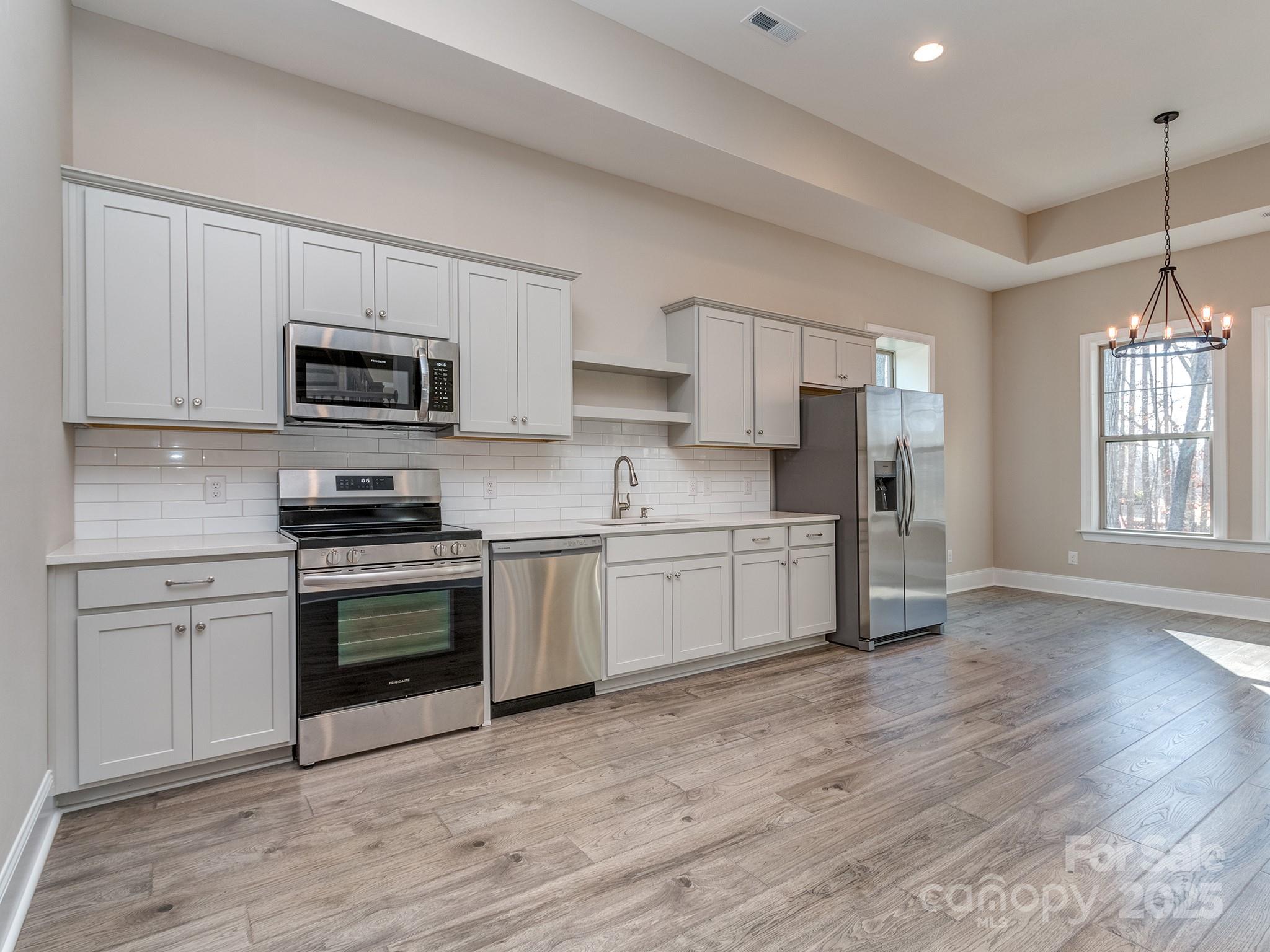 11055 Holiday Cove Lane Tega Cay, SC 29708 - Photo 23 of 39 a kitchen with stainless steel appliances granite countertop a stove top oven a sink dishwasher and a refrigerator with wooden floor
