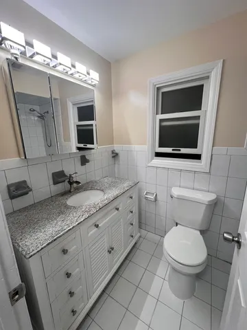 a bathroom with a granite countertop toilet sink and mirror