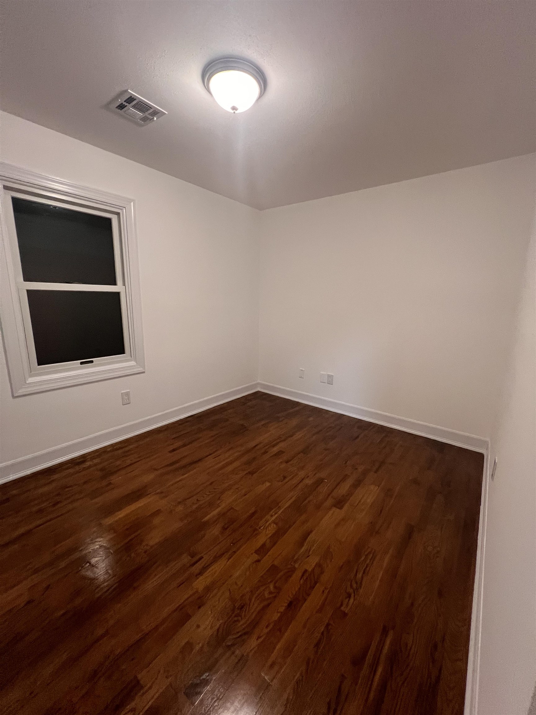 1302 Morris Street Union City, NJ 07087 - Photo 8 of 12 a view of an empty room with wooden floor and a window