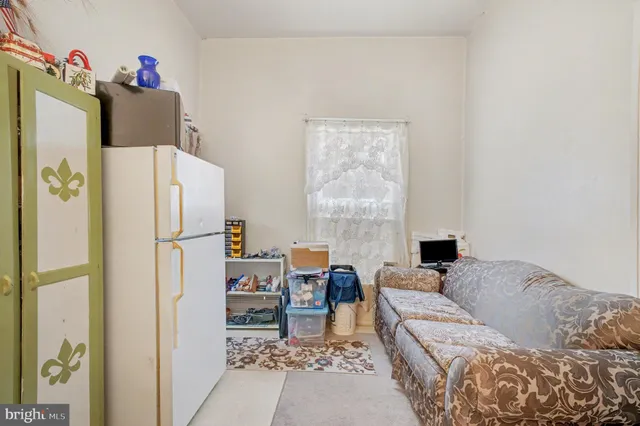 a living room with furniture and a refrigerator