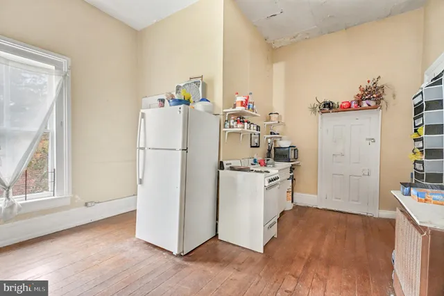 a kitchen with a refrigerator a stove top oven and a wooden floor