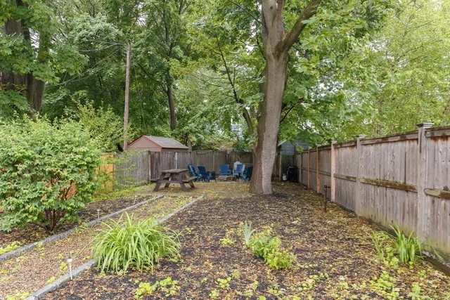 a view of a backyard with wooden fence and a large tree