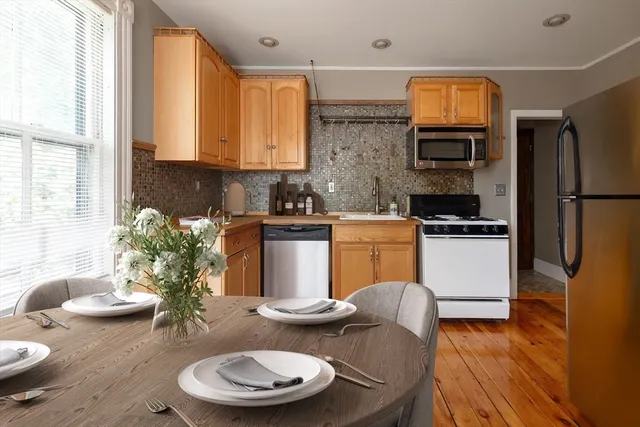 a kitchen with stainless steel appliances granite countertop a stove a sink a refrigerator dining table and chairs