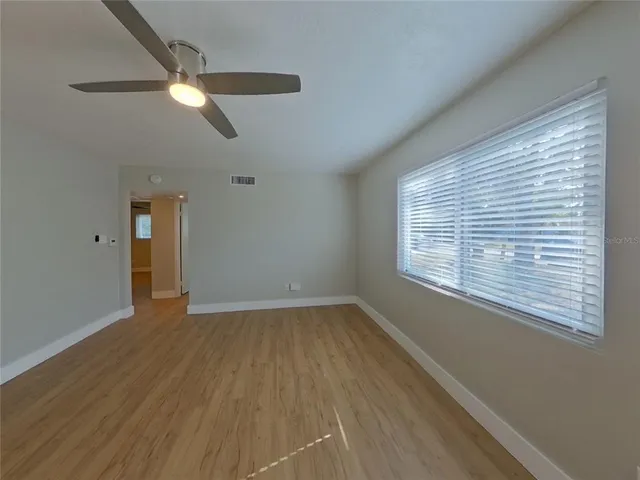 a view of an empty room with wooden floor and a window