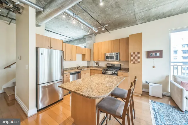 a kitchen with stainless steel appliances granite countertop a refrigerator a stove and a sink with couches