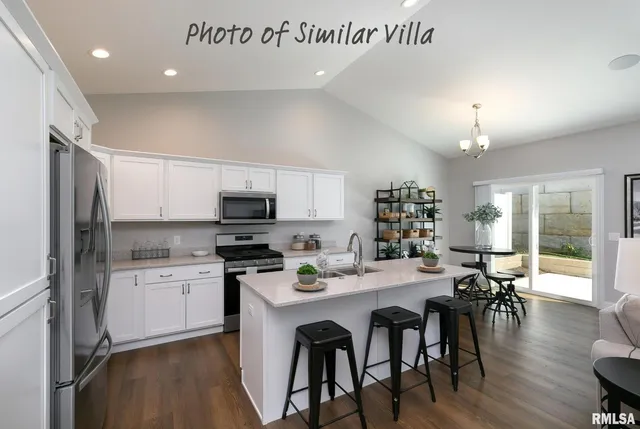 a kitchen with a dining table cabinets appliances and wooden floor