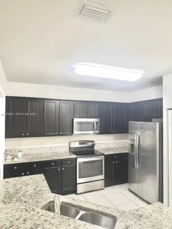a kitchen with granite countertop a refrigerator and a stove top oven