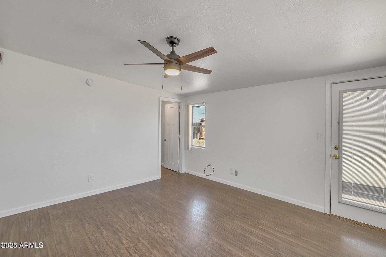 1526 West Huntington Drive Tempe, AZ 85282 - Photo 11 of 17 an empty room with wooden floor ceiling fan and windows
