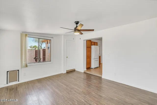 a view of an empty room with window and wooden floor