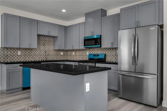 a kitchen with stainless steel appliances granite countertop a refrigerator a stove a sink and a microwave