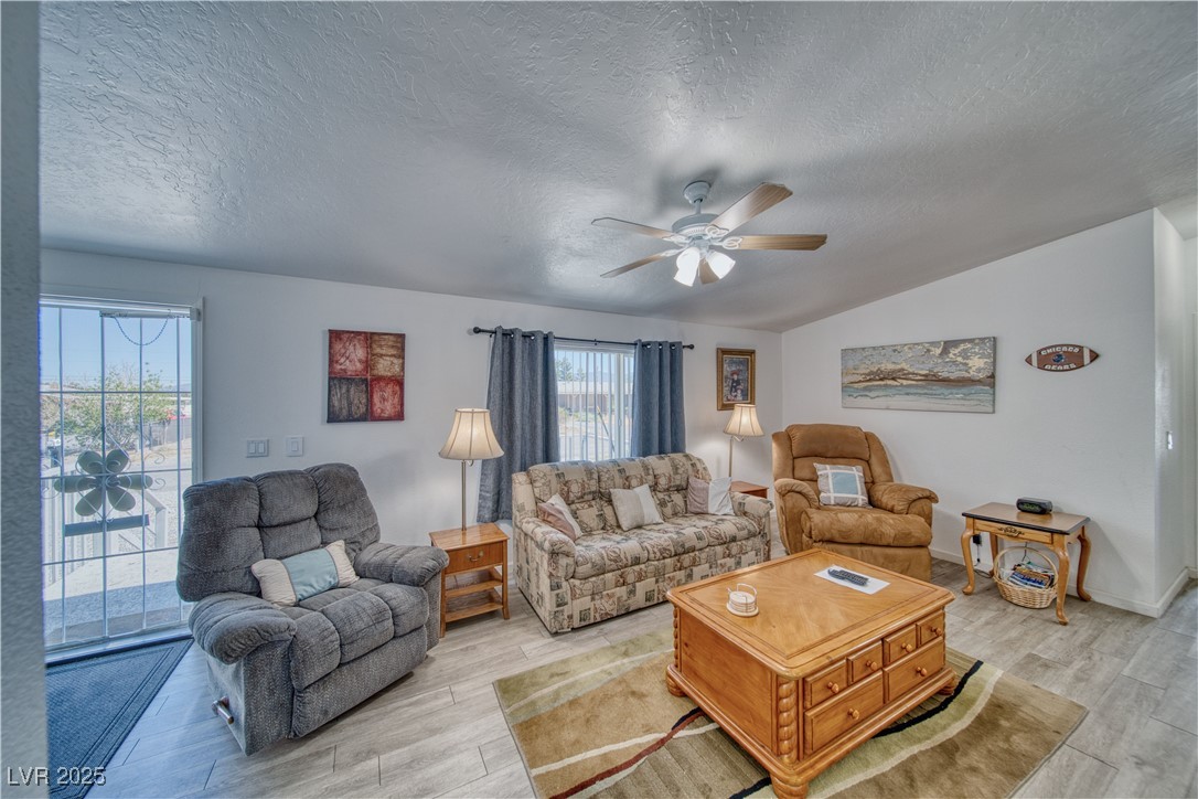 Living room with light wood finished floors, a ceiling fan.