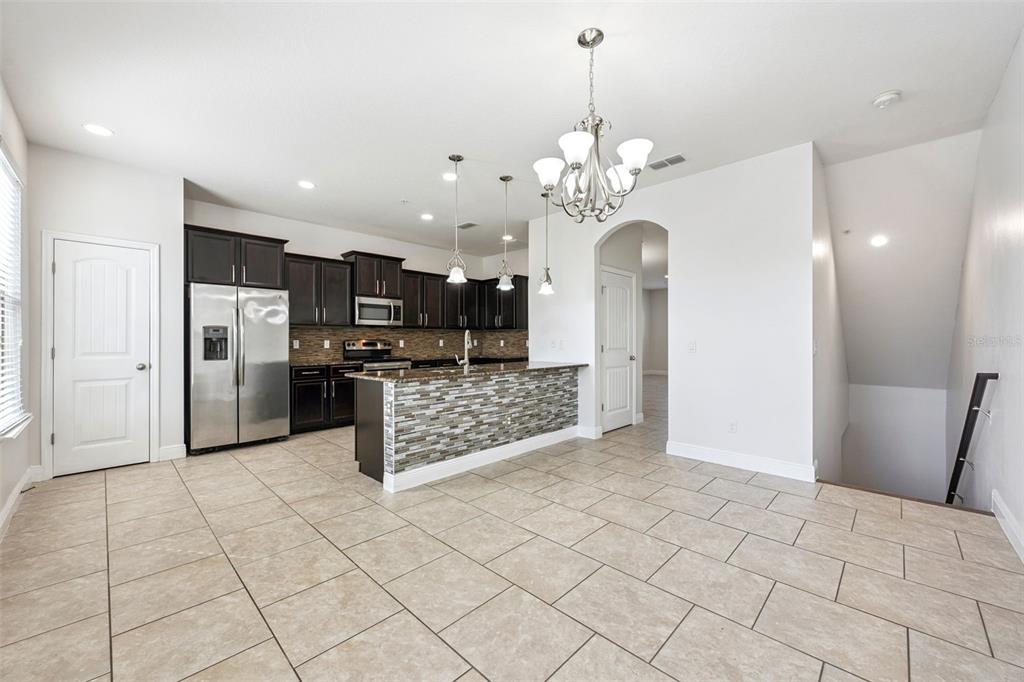 10866 Sunset Ridge Lane Orlando, FL 32832 - Photo 20 of 74 a large kitchen with stainless steel appliances kitchen island granite countertop a refrigerator and a stove top oven