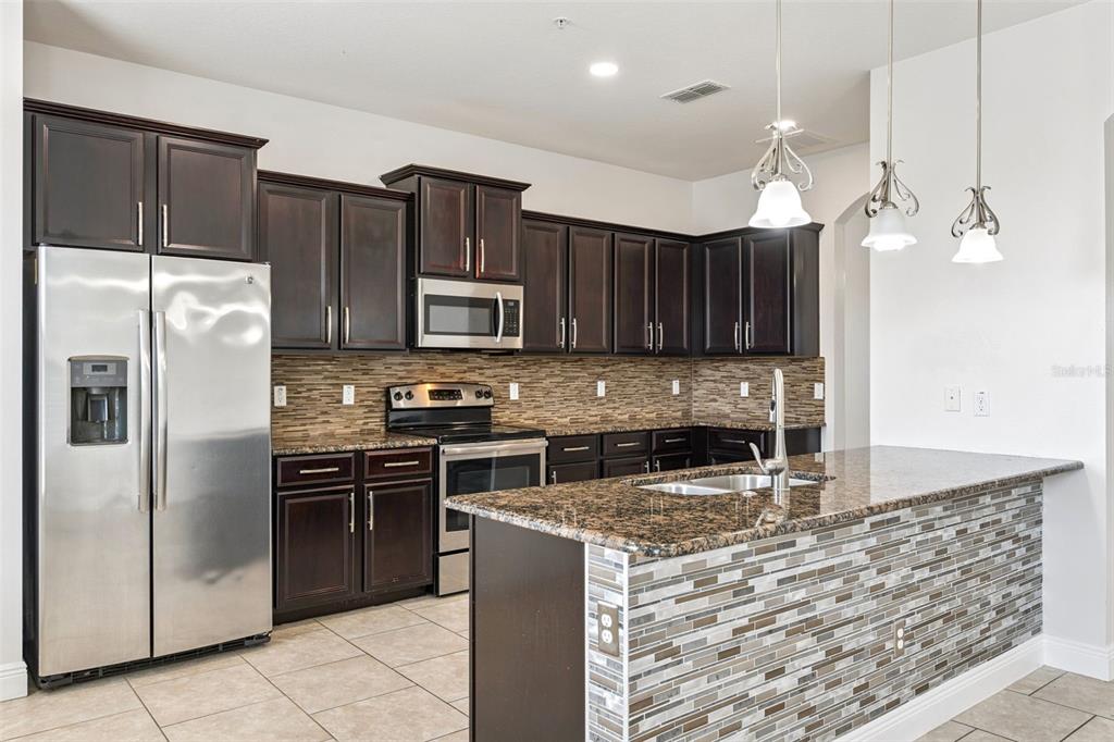 10866 Sunset Ridge Lane Orlando, FL 32832 - Photo 4 of 74 a kitchen with stainless steel appliances granite countertop a refrigerator a stove a sink and a microwave