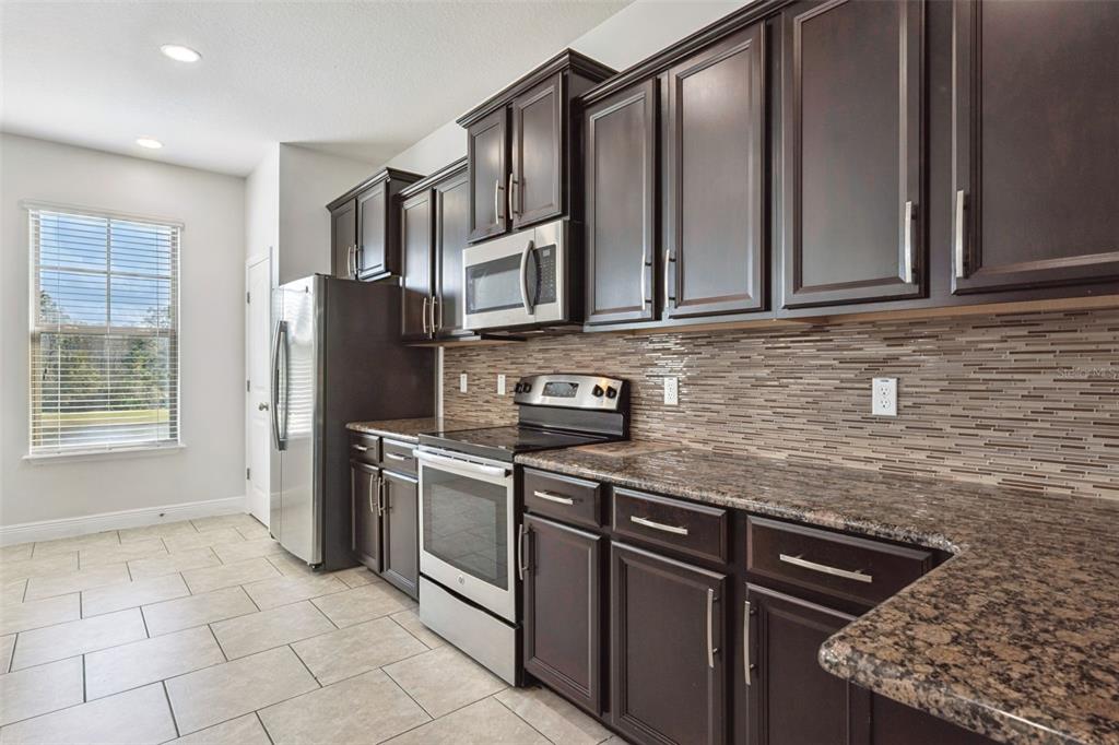 10866 Sunset Ridge Lane Orlando, FL 32832 - Photo 5 of 74 a kitchen with stainless steel appliances granite countertop a sink stove and refrigerator