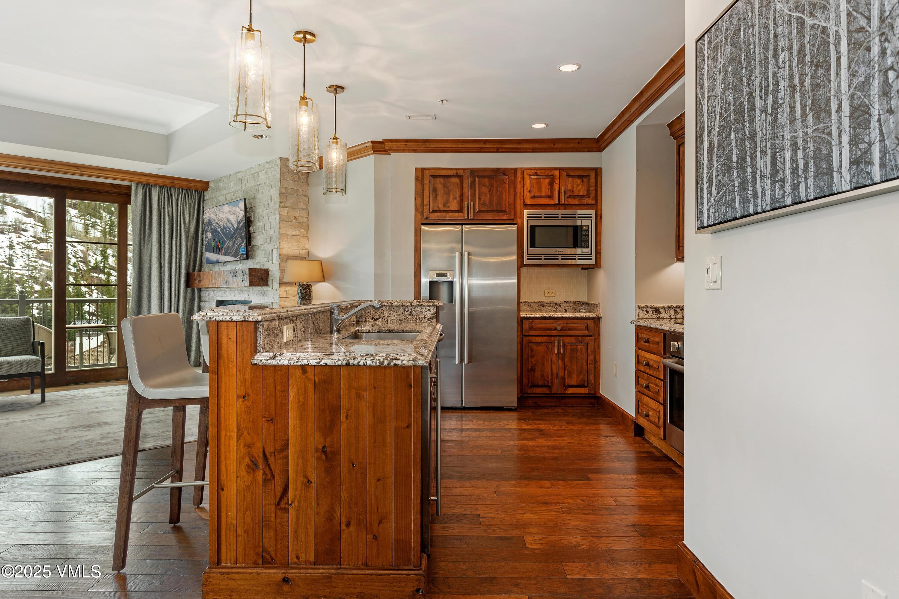 728 West Lionshead Circle, Unit F429 Vail, CO 81657 - Photo 16 of 25 a kitchen with stainless steel appliances granite countertop a refrigerator a stove and a wooden floors
