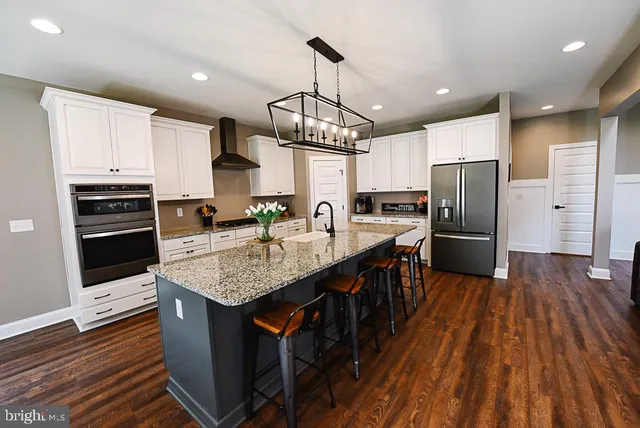 a kitchen with stainless steel appliances a kitchen island hardwood floor sink stove microwave and cabinets