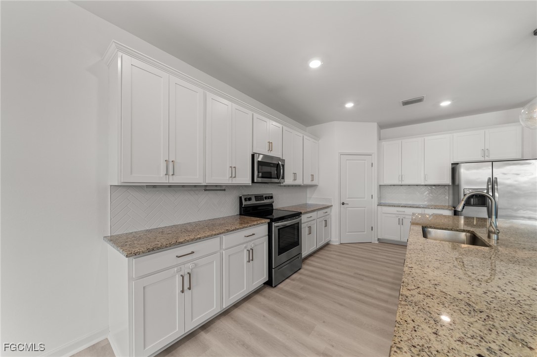 11559 Canopy Loop Fort Myers, FL 33913 - Photo 16 of 50 a kitchen with granite countertop a sink stainless steel appliances and white cabinets